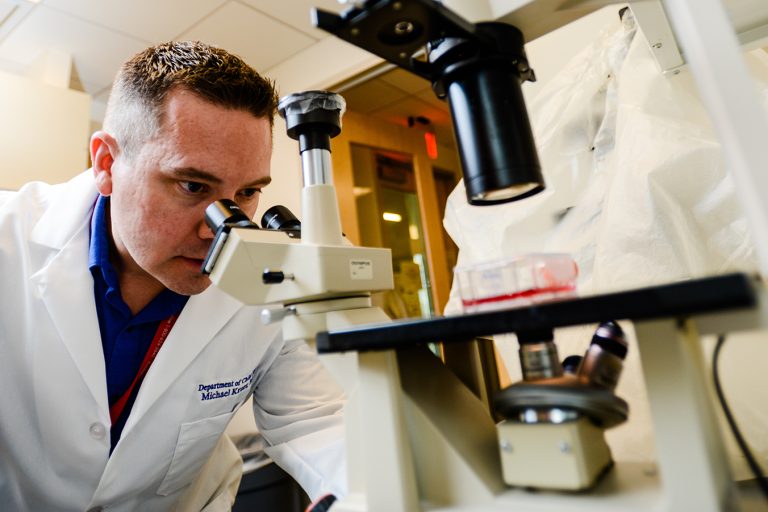 doctor looking through a large microscope