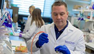 Male scientist pipetting into a tube