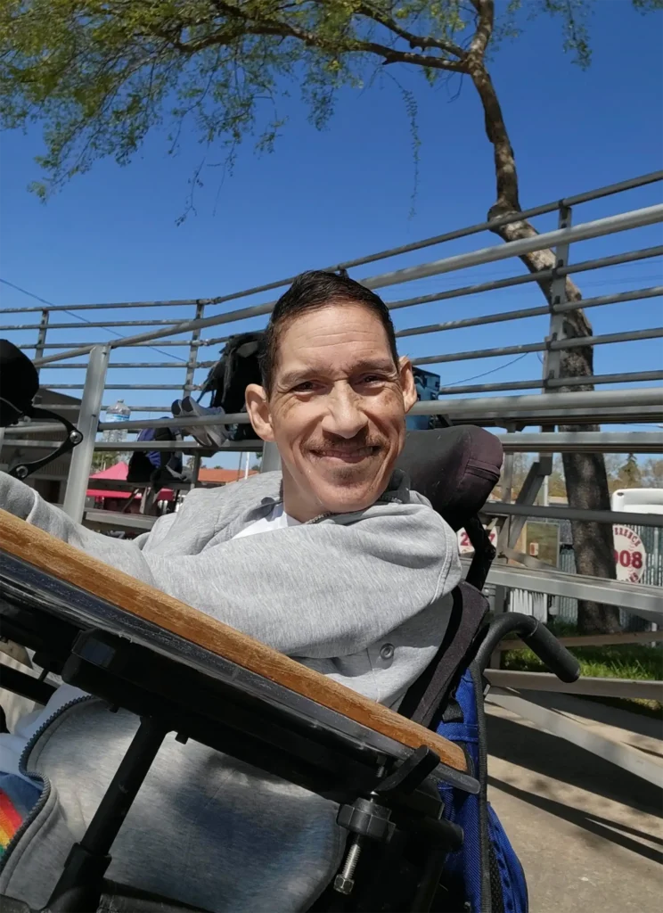 A medium closeup of man in a wheelchair smiling on a sunny day.