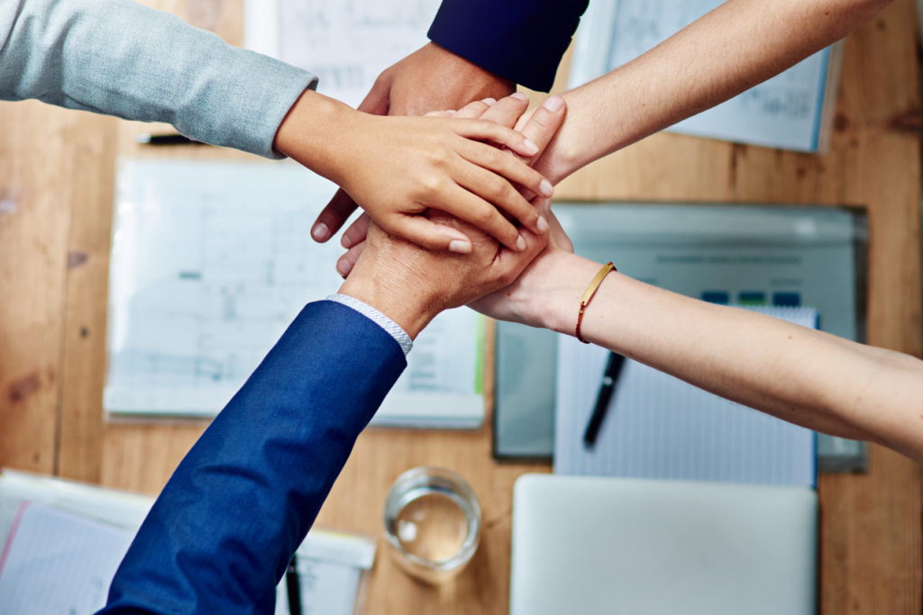 hands banded together over desktop symbolizing teamwork