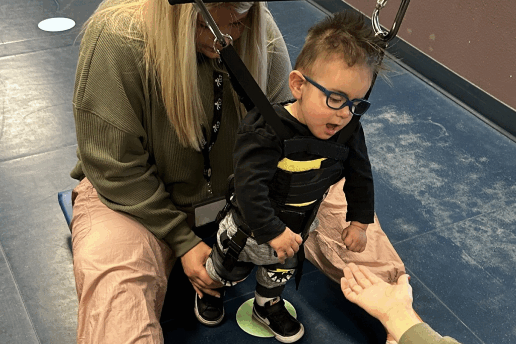 Child with cerebral palsy walking with the help of trainers and therapist
