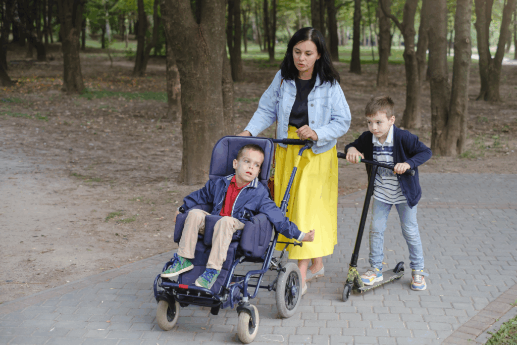 Mother with her two sons taking a walk, she pushes one of her sons in a wheelchair