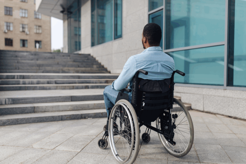 A man in a wheelchair looks on toward a flight of stairs