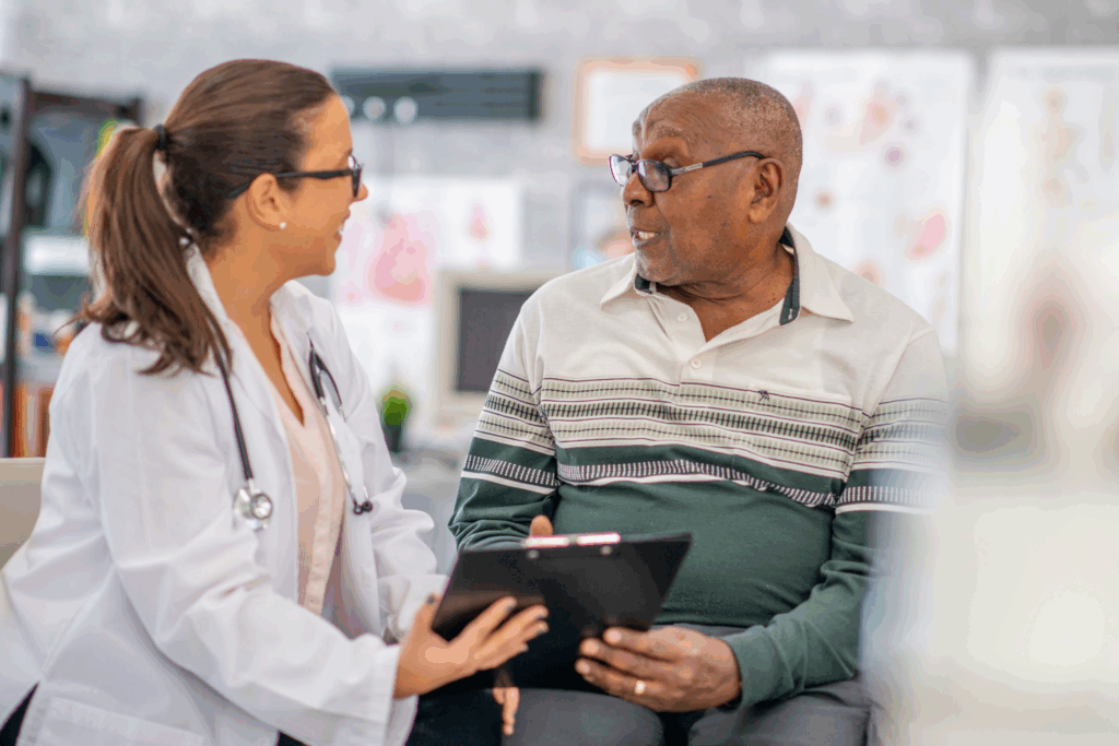 Adult man talking to his medical provider, who is holding a clipboard