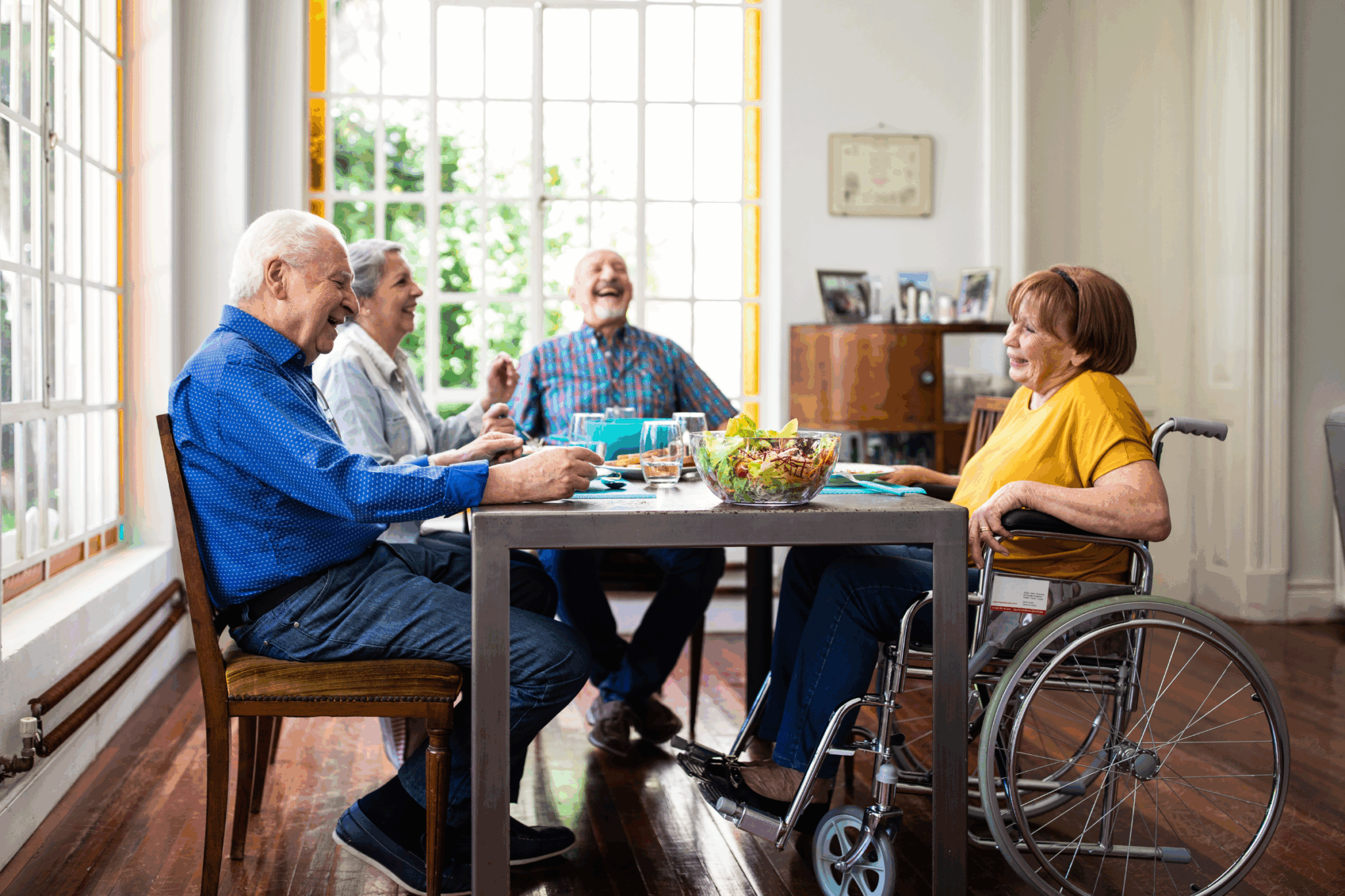 A group of elderly people sitting around a table one is in a wheelchair