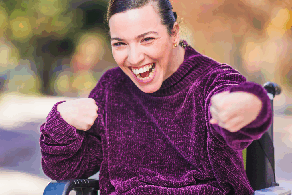 Female adult with cerebral palsy smiling and wearing a purple sweater