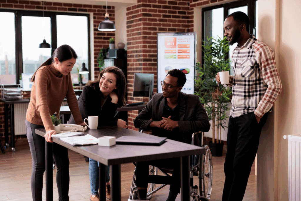 a group of coworkers around a table, one of them is in a wheelchair