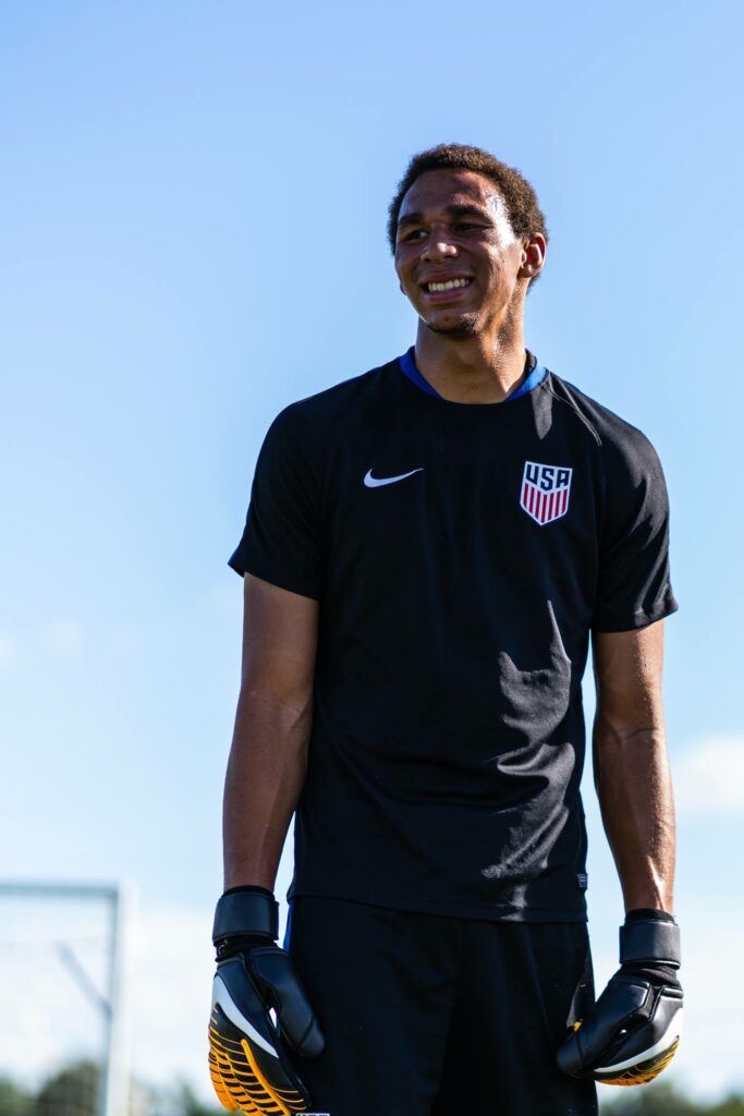 Matt Downing wearing a blue US Soccer jersey standing with a smile