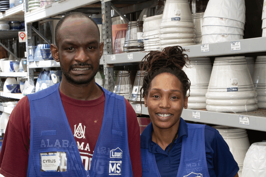 Man in a blue Lowes vest and a woman smiling in the garden center