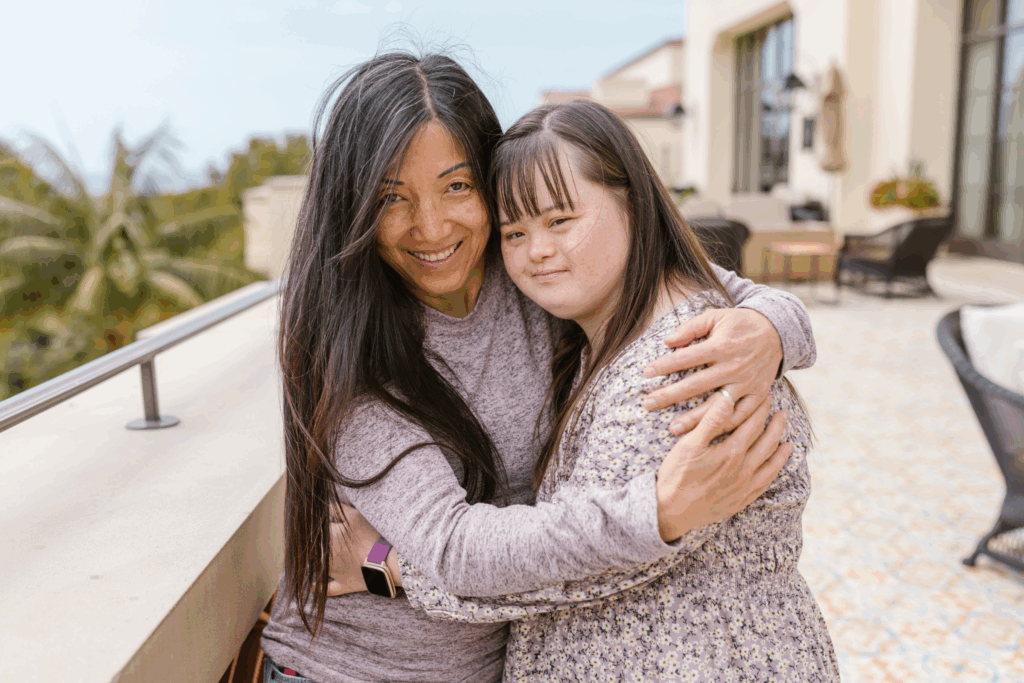 a woman stands with a girl with Down syndrome, they are embracing