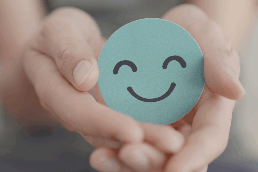 blue smiling emoji held in a pair of hands