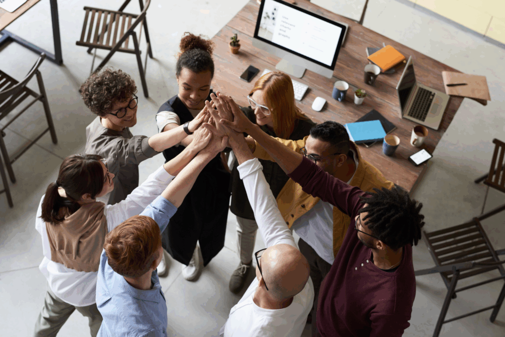 group of workers in an office putting their hands together in the spirit of teamwork