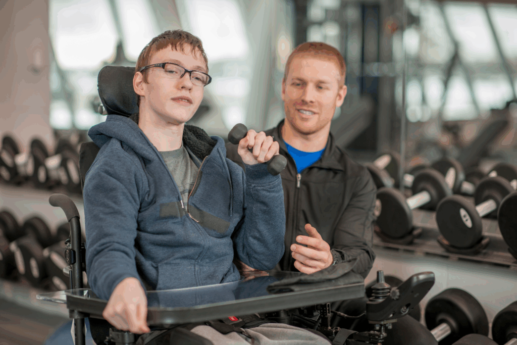 person in a wheelchair lifting weights with a personal trainer
