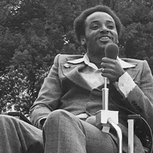 Brad Lomax, disability rights champion, holds a microphone at a rally