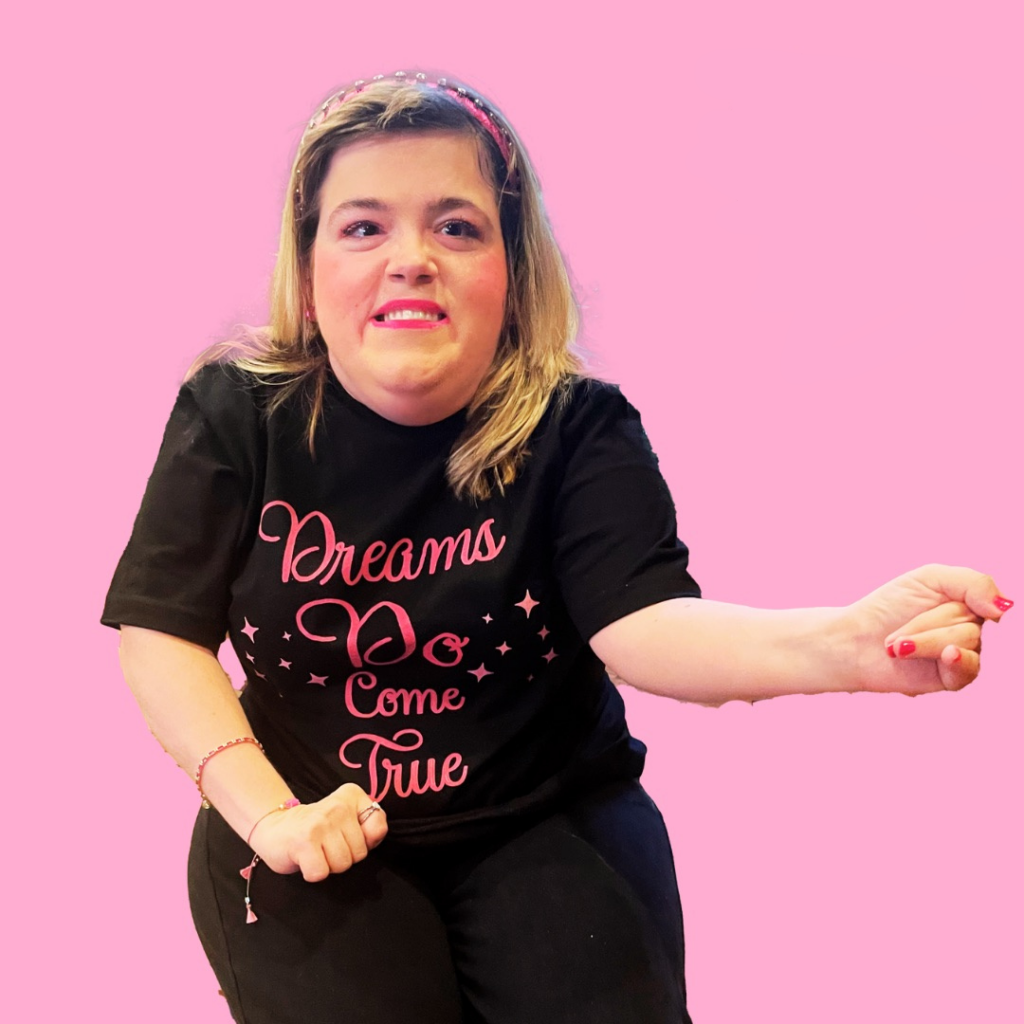 a girl wearing a black tshirt with a pink design on a pink background