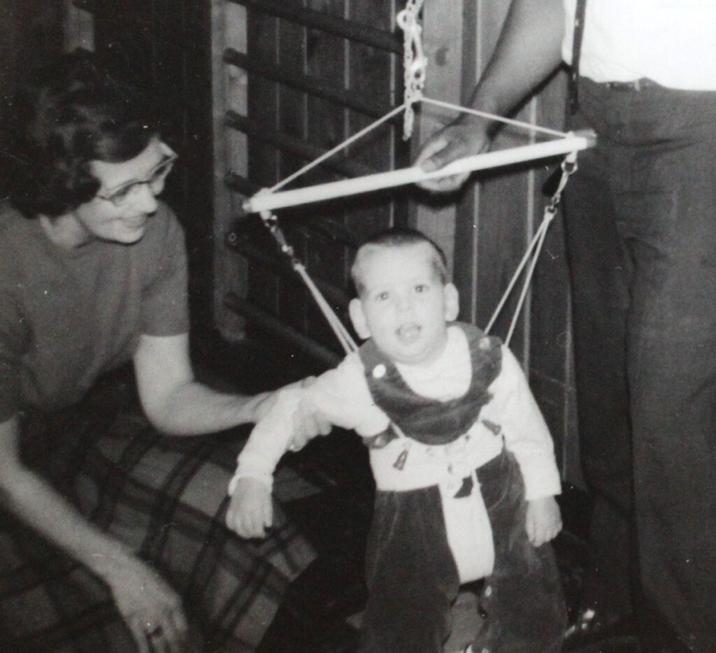 a black and white photo of a mother assisting a child in a harness